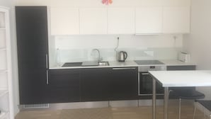 Ett modernt kök med vita skåp, en svart bänkskiva, en vattenkokare och en brödrost.