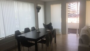 En matplats med ett bord och stolar, en golvlampa och utsikt genom ett fönster.