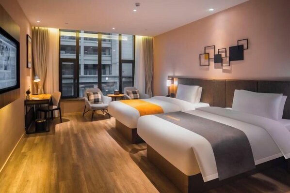 A hotel room with two beds, a desk, a chair, a small table, and a large window with curtains.