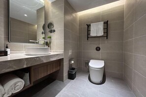 Un baño moderno con un espejo grande, un lavabo, un inodoro y un perchero para toallas.