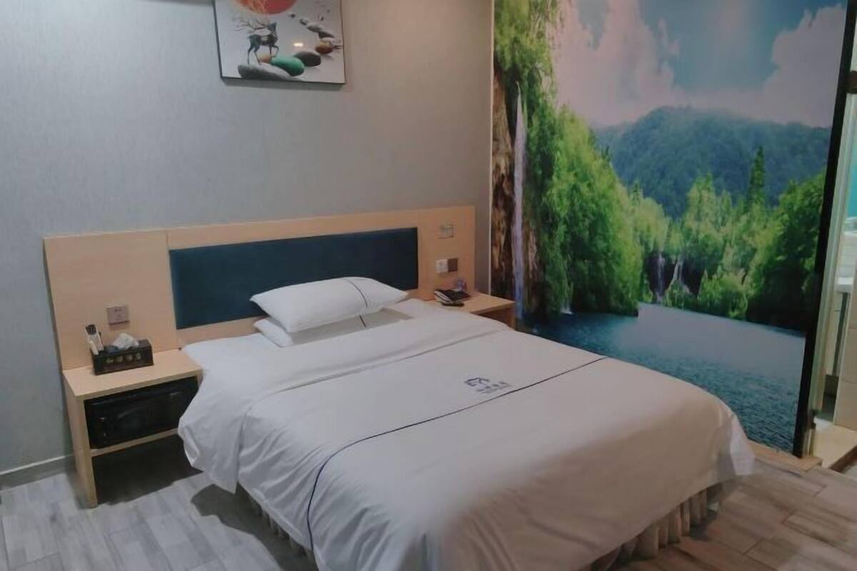 Een hotelkamer met een bed, nachtkastjes, een schilderij aan de muur en een sfeervol muurschildering.