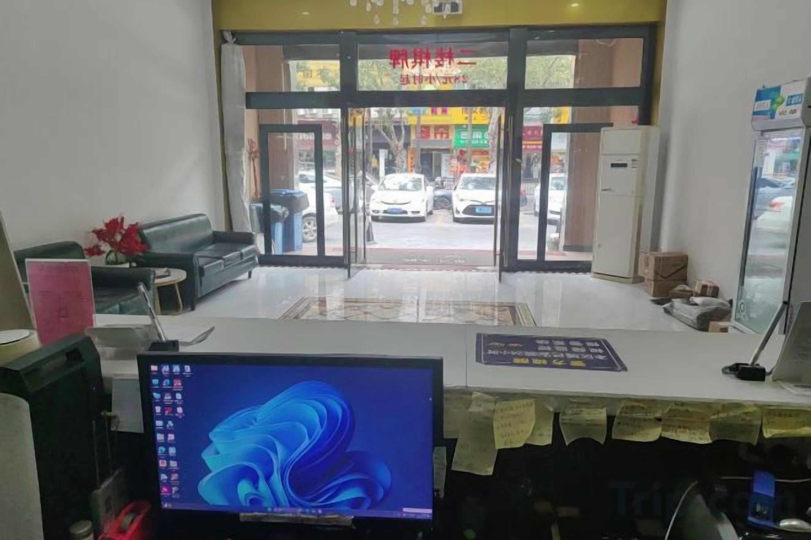 A reception area with a computer monitor, a sofa, a coffee table, and a reception desk.