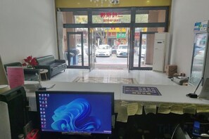 Un espace d’accueil comprenant un écran d’ordinateur, un canapé, une table basse et un comptoir de réception.