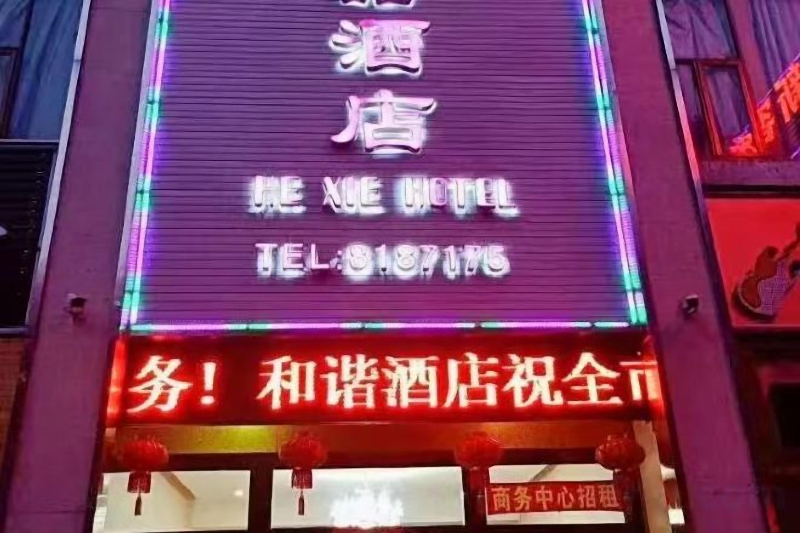 A hotel sign with neon lights and a contact number.