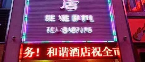 A hotel sign with neon lights and a contact number.