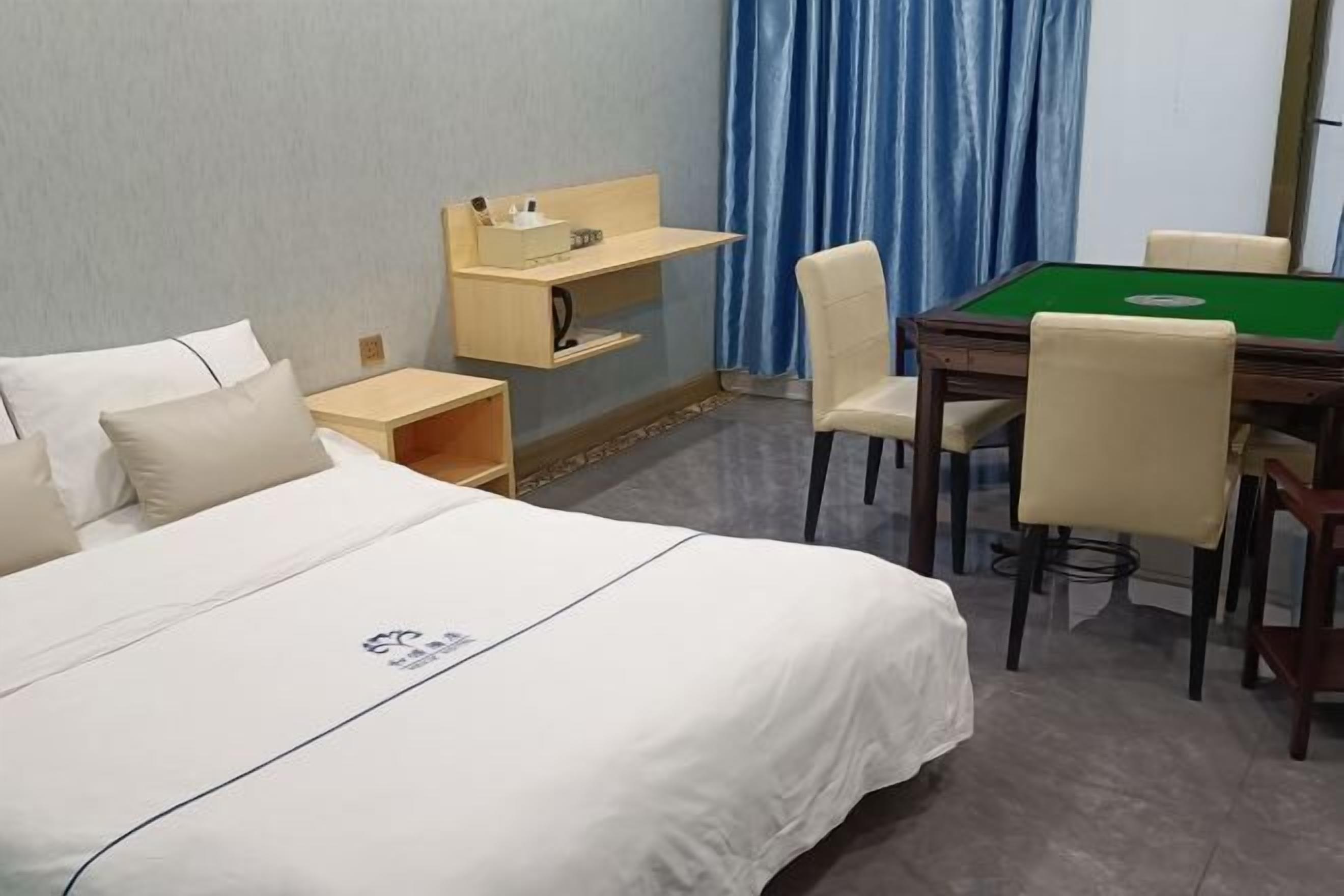 Une chambre d’hôtel avec un lit, un bureau et une chaise, une table de billard verte et un rideau bleu.