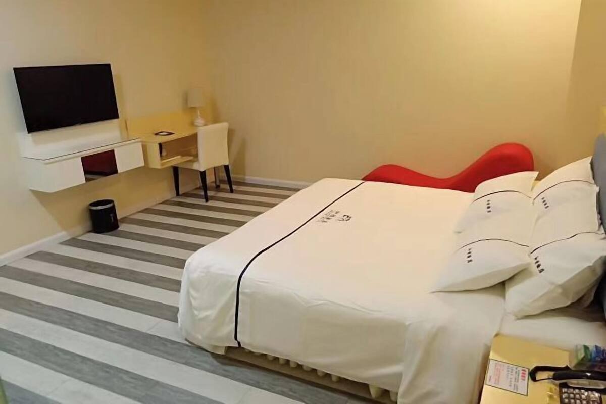 Een hotelkamer met een bed, een televisie, een bureau en een stoel.