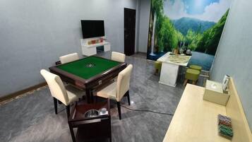 A room with a pool table, comfortable seating, a small bar area, and a large mural of a landscape.