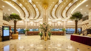 A spacious lobby with a polished marble floor, a central floral arrangement, and a bar area with a checkered floor pattern. - Sky & Sea Resort (Chongqing)