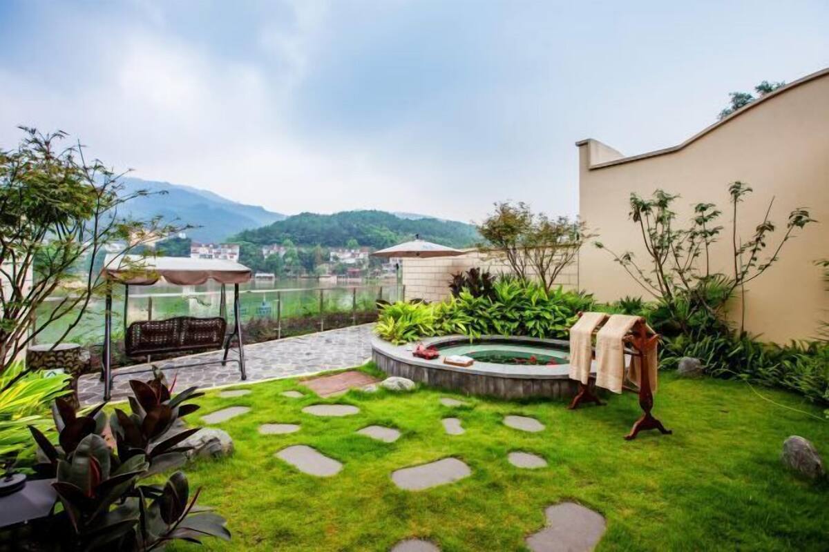 A garden with a hot tub, a pergola, and a view of mountains.