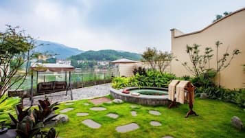 A garden with a hot tub, a pergola, and a view of mountains.