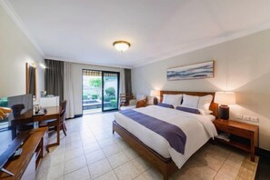 A hotel room with a bed, a desk, a chair, a TV, a lamp, and a painting on the wall. - Sky Sea Resort (Chongqing)