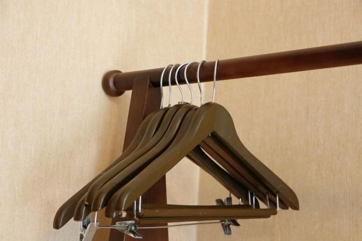 A wooden coat rack with multiple hangers.