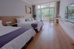 A hotel room with two beds, a large window with a view of greenery, a balcony, and a fan. - Sky Sea Resort (Chongqing)