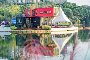 A floating house with a red upper level and a white lower level, situated on a calm lake with reflections. - Sky Sea Resort (Chongqing)