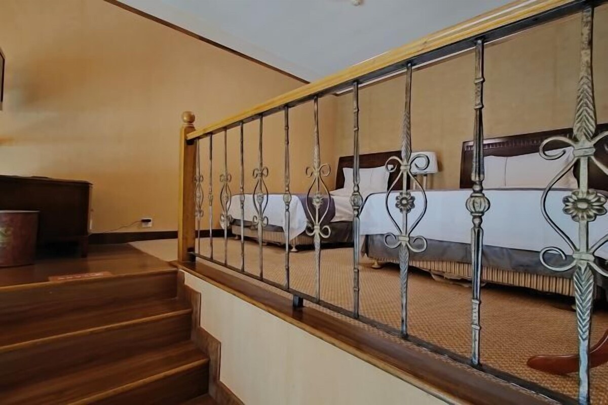 A staircase with a wooden handrail and metal balusters leading to a bedroom with two beds.