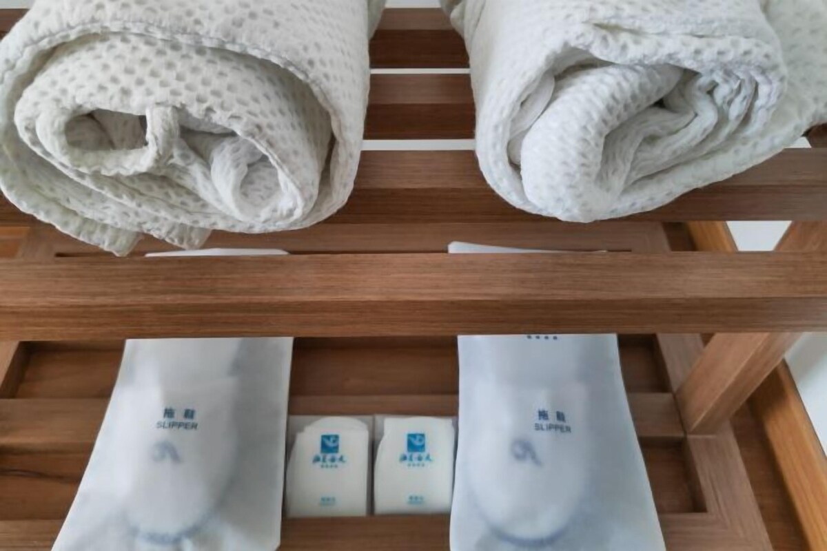 A wooden rack with folded towels and a set of slippers.