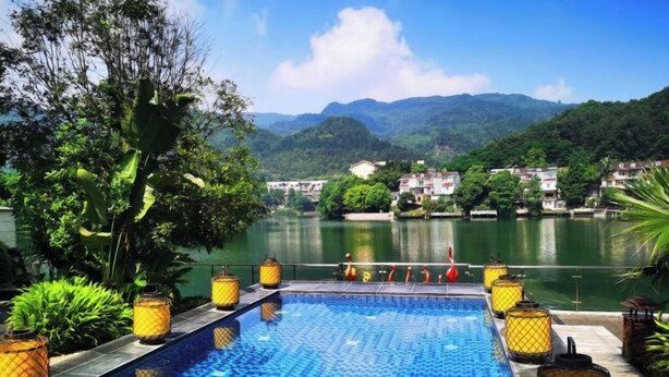 A rectangular pool with a mosaic tile pattern, surrounded by potted plants and yellow lanterns. - Sky & Sea Resort (Chongqing)