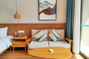 A hotel room with a bed, a sofa, a round table, a nightstand, a wall-mounted artwork, and a window with curtains. - Sky Sea Resort (Chongqing)