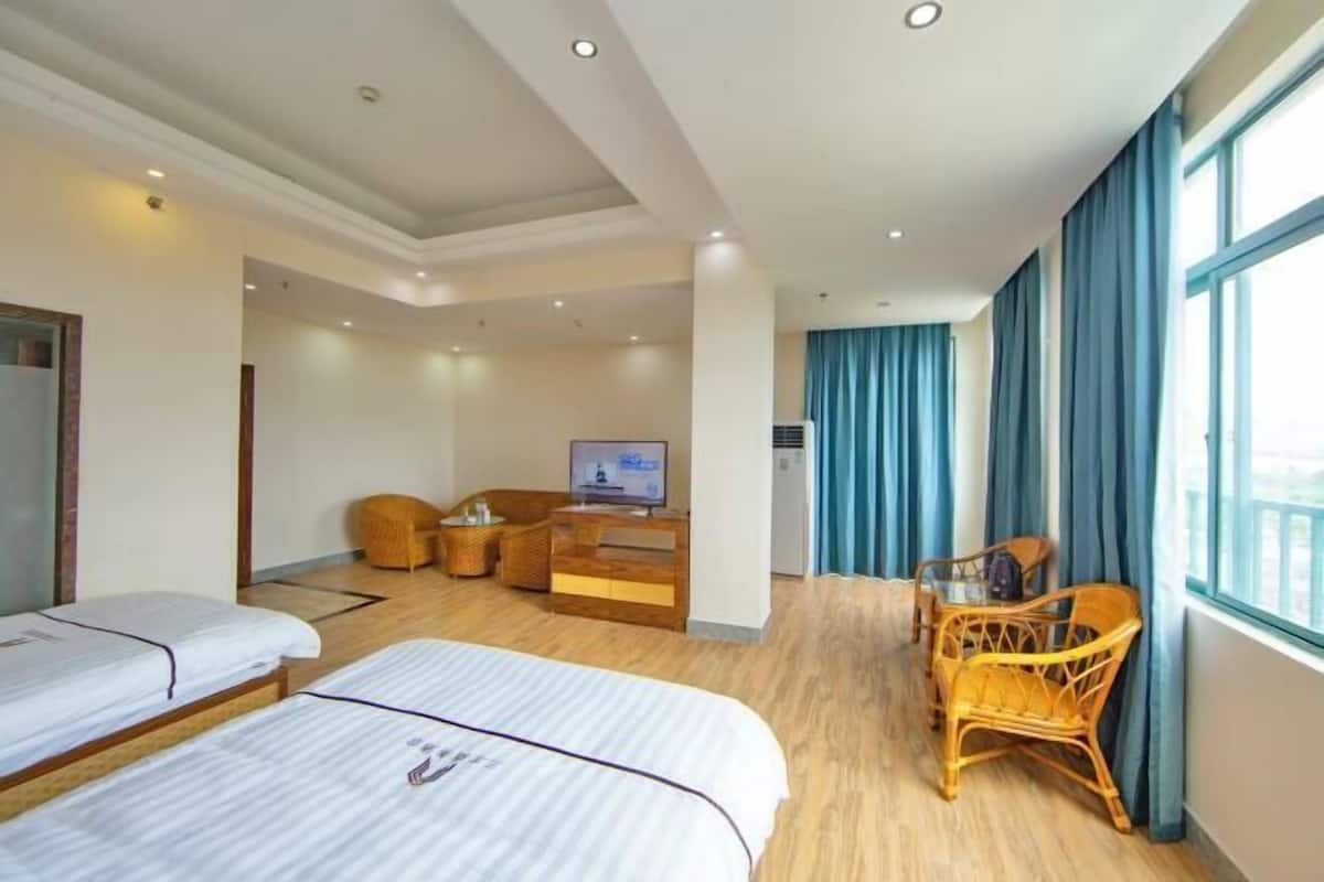 Ein Hotelzimmer mit zwei Betten, einem Fernseher, einer Couch und einem Esstisch.