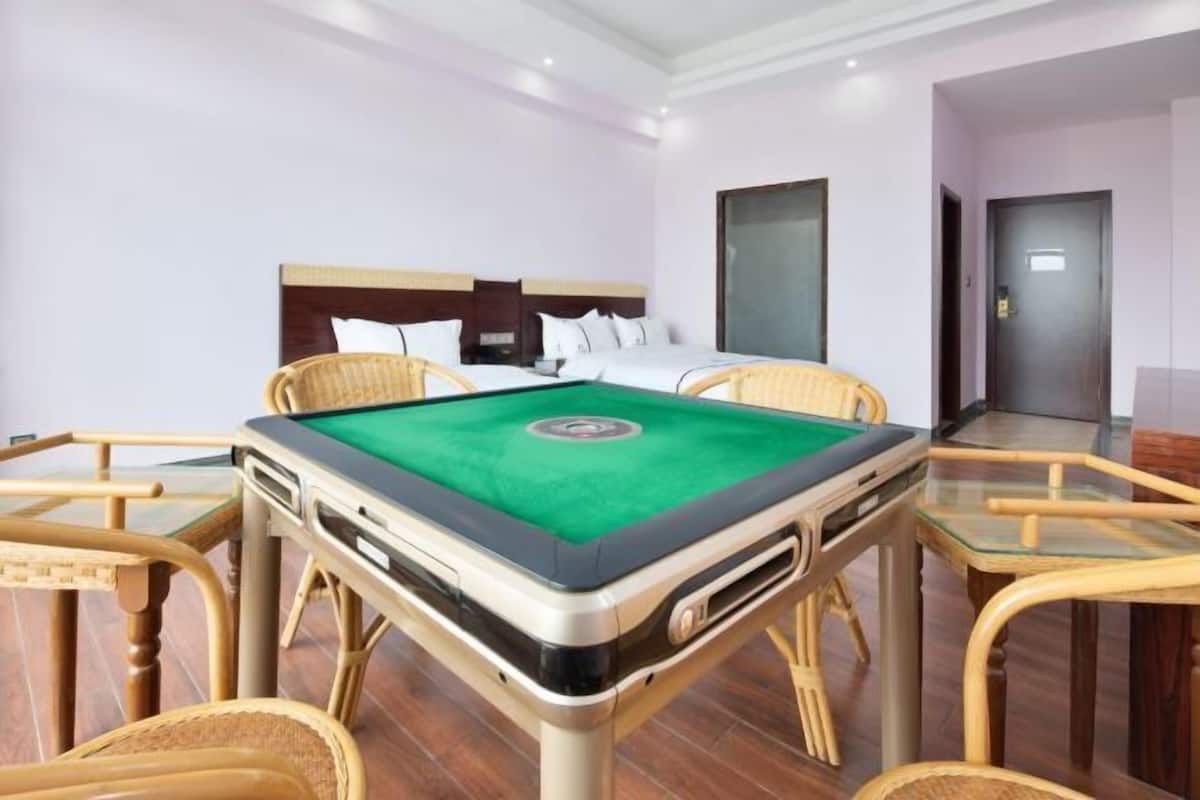 Ein Hotelzimmer mit Billardtisch, einem Bett und Korbstühlen.