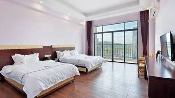 A hotel room with two beds, a TV, a desk, and a balcony with a view.