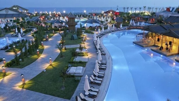 A resort with a large swimming pool, lounge chairs, and a well-lit walkway. - Lingshui Sancai Business Hotel (Lingshui)