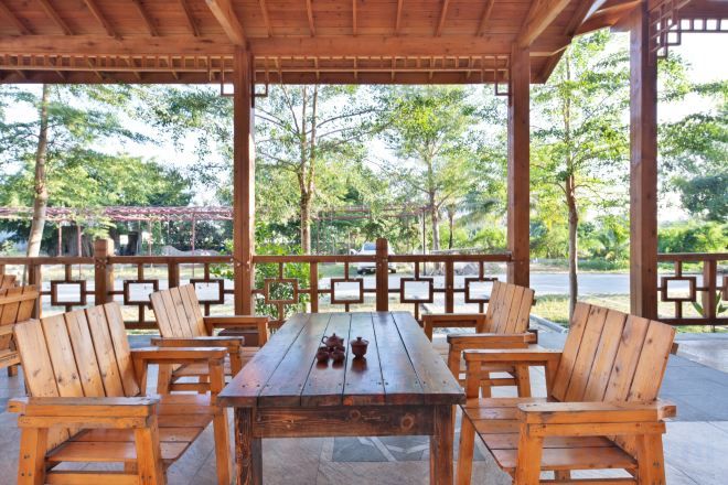 An outdoor wooden deck with a table and chairs, surrounded by a wooden railing.