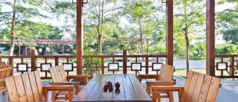 An outdoor wooden deck with a table and chairs, surrounded by a wooden railing.