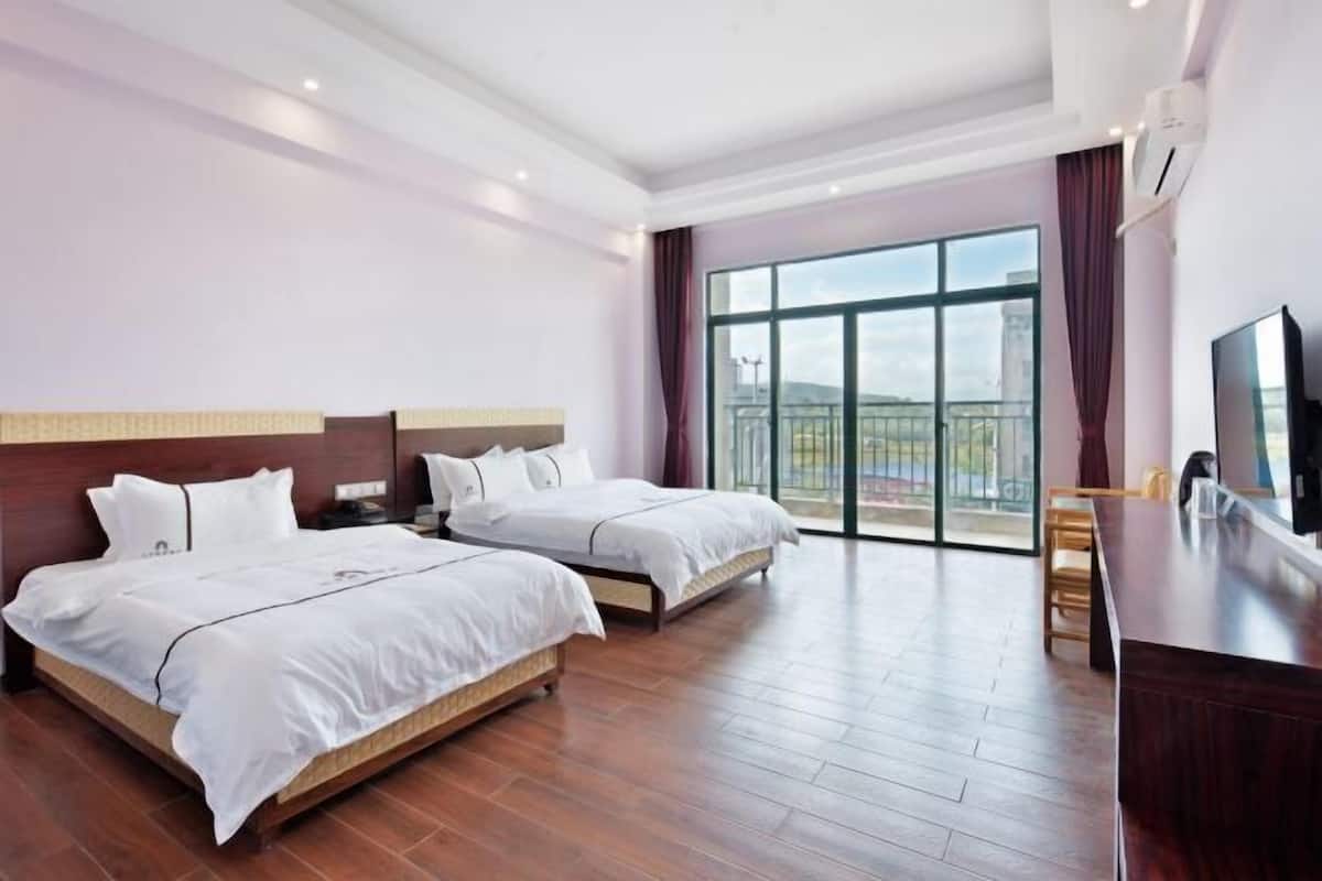 Ein Hotelzimmer mit zwei Betten, einem Fernseher, einem Schreibtisch und einem Balkon mit Blick.