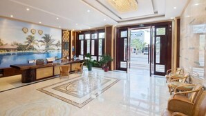 A hotel lobby with a reception desk, seating area, and a large window. - Lingshui Sancai Business Hotel (Lingshui)