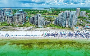 A coastal resort with high-rise buildings, a sandy beach, and a clear view of the ocean.