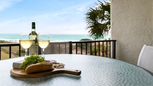 A table with a bottle of wine, two glasses, grapes, a baguette, and crackers on a glass table with a view of the ocean. - CostaVista-Sandestin: Steps to Beach/Gulf Views! (Miramar Beach)