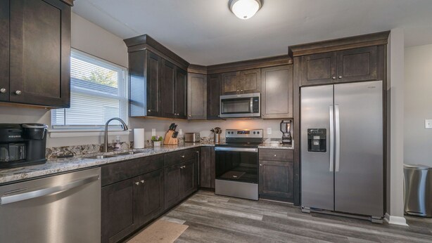 A modern kitchen with dark wood cabinets, stainless steel appliances, and a granite countertop. - Spacious 3BR in Phoebus - Great Monthly Rates (Hampton)
