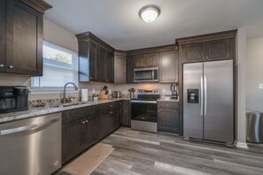 A modern kitchen with dark wood cabinets, stainless steel appliances, and a granite countertop. - Spacious 3BR in Phoebus - Great Monthly Rates (Hampton)
