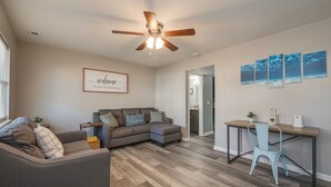 A modern living room with a sofa, a desk, and a ceiling fan. - Spacious 3BR in Phoebus - Great Monthly Rates (Hampton)