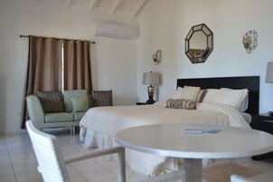 A hotel room with a bed, a sofa, a round table, and a lamp.