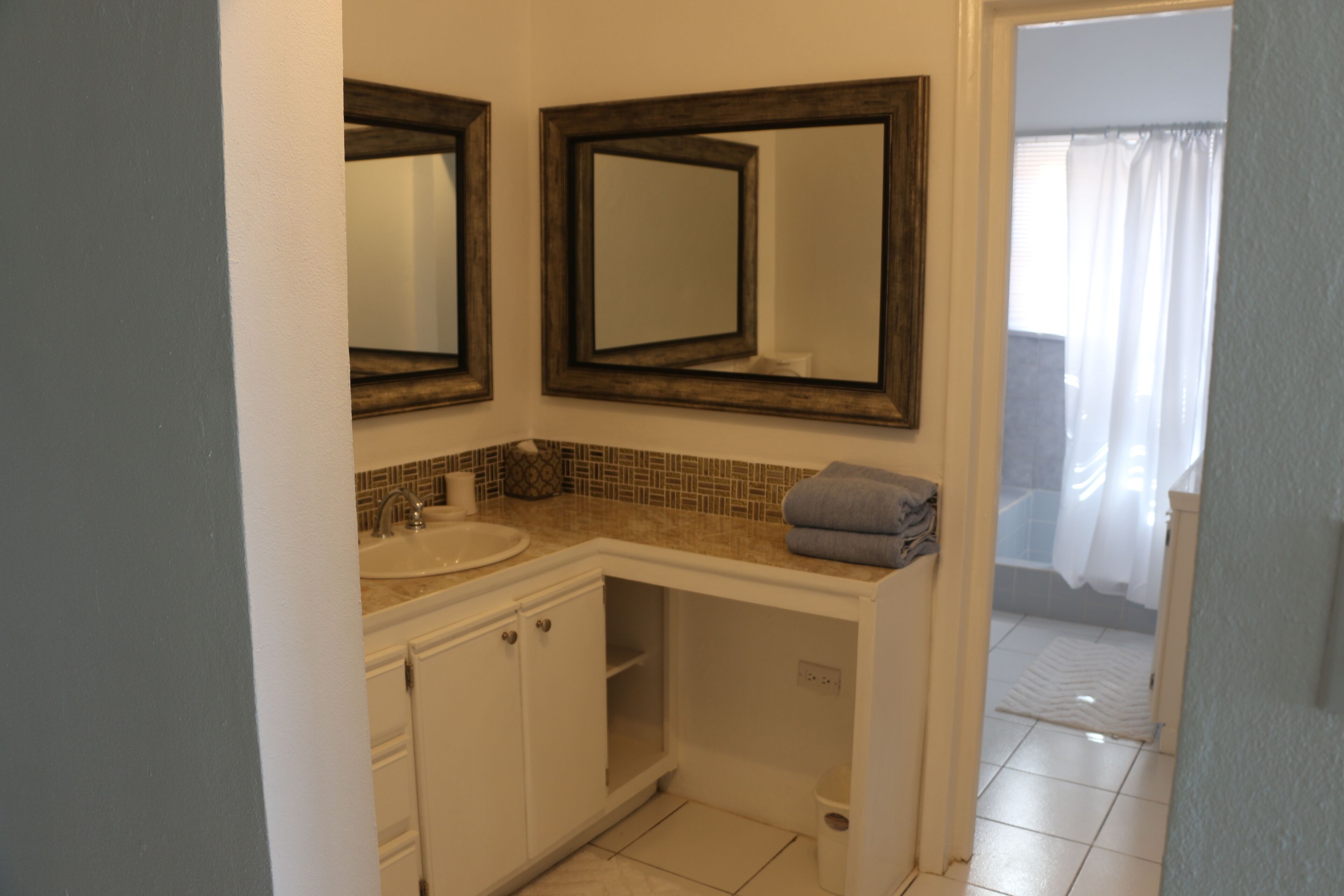 Une salle de bain avec deux miroirs, un lavabo et un porte-serviettes.