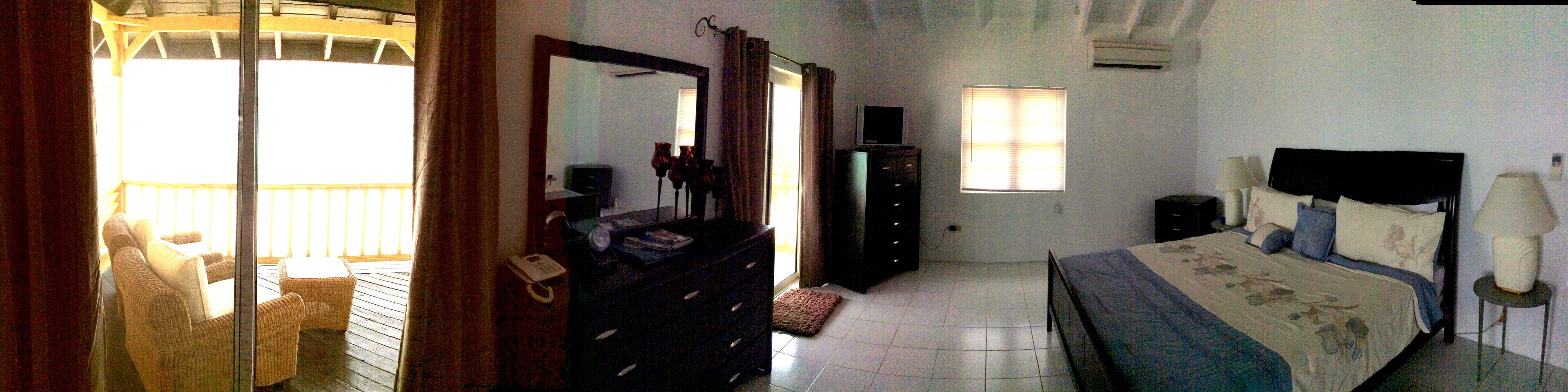 A bedroom with a bed, dresser, and a TV on a stand.