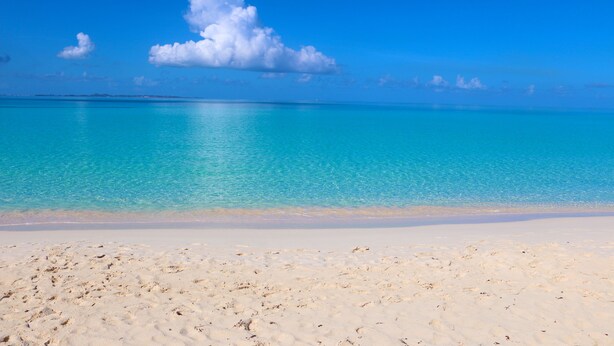 Una playa con agua turquesa cristalina y una orilla de arena blanca.