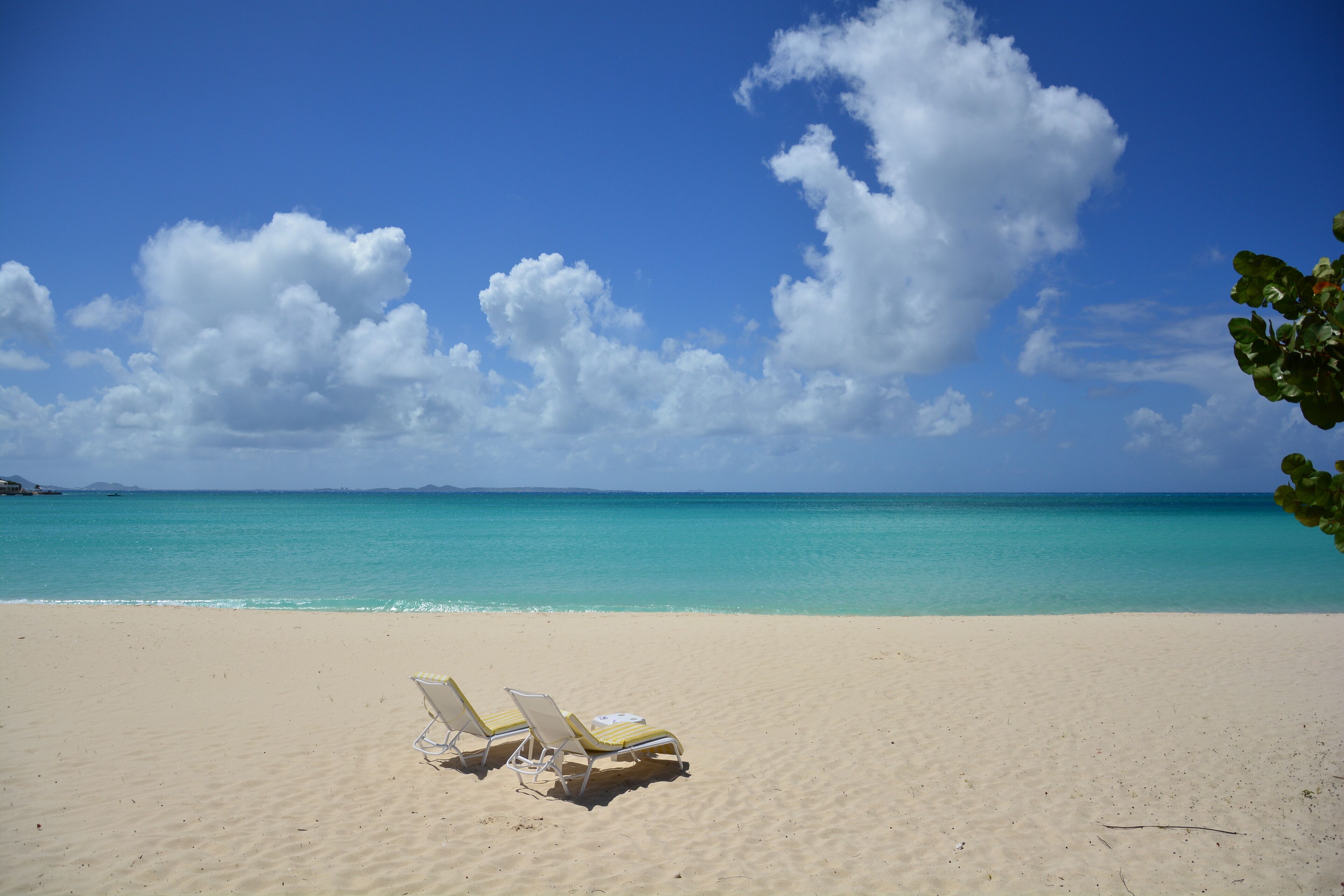 A beach with two sun loungers and a clear view of the ocean.
