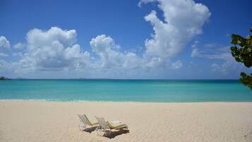 A beach with two sun loungers and a clear view of the ocean.