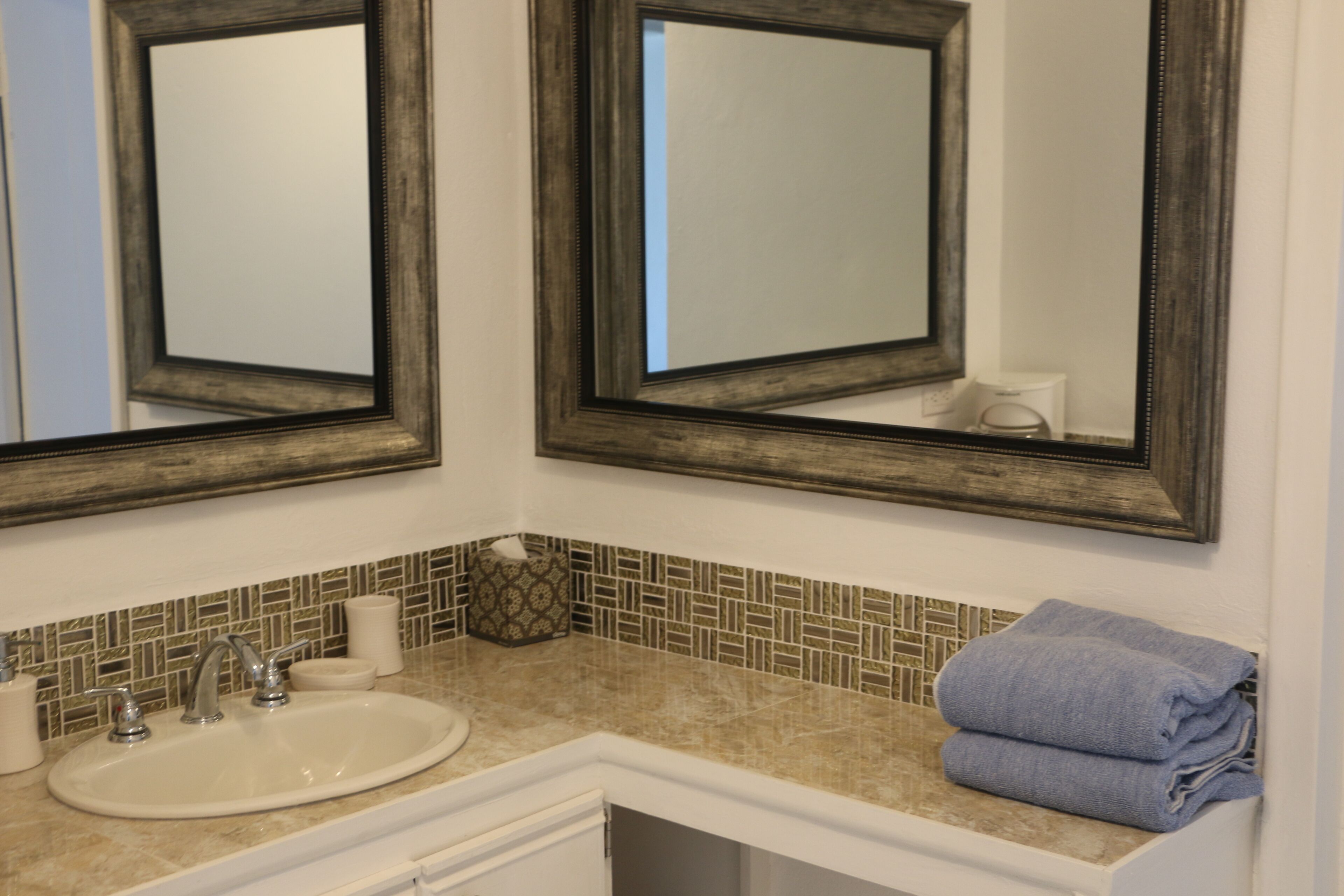 A bathroom with two mirrors, a sink, and a towel rack.