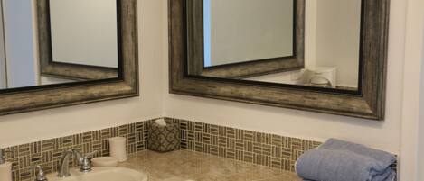 A bathroom with two mirrors, a sink, and a towel rack.