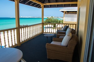 A covered balcony with wicker furniture and a view of the ocean.