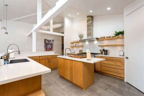 Una cucina moderna con isola centrale, mobili in legno e schienale piastrellato.