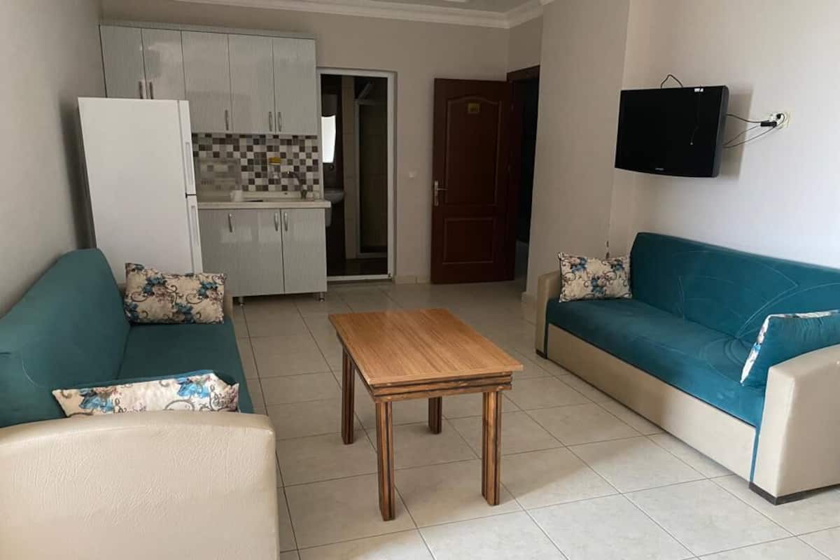 Un salon avec un canapé, une table basse et un téléviseur fixé au mur.