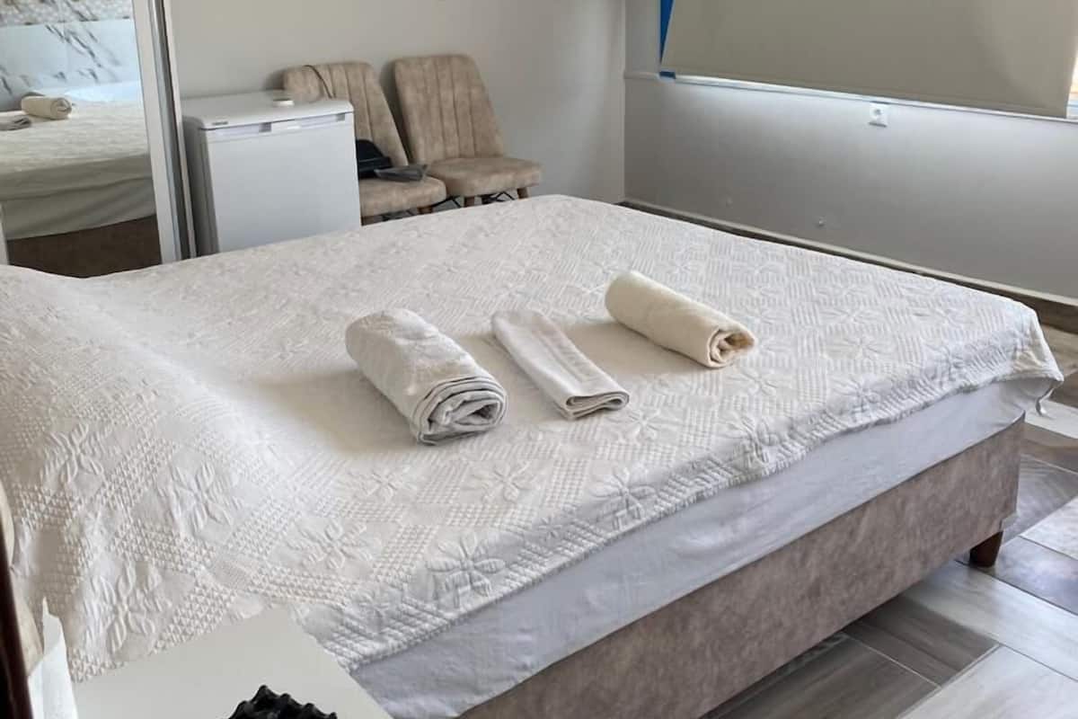 Une chambre d’hôtel avec un lit, un téléviseur fixé au mur, un petit bureau et une fenêtre donnant sur un paysage agréable.