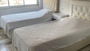 Et hotelværelse med to senge, et vindue og et flisegulv.