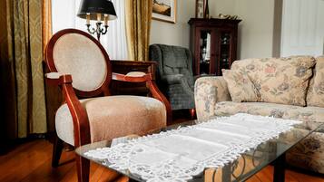 A living room with a glass coffee table, a wooden chair, a sofa, a lamp, and a cabinet.